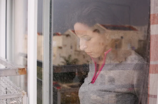 Kobieta patrząc przez okno — Zdjęcie stockowe