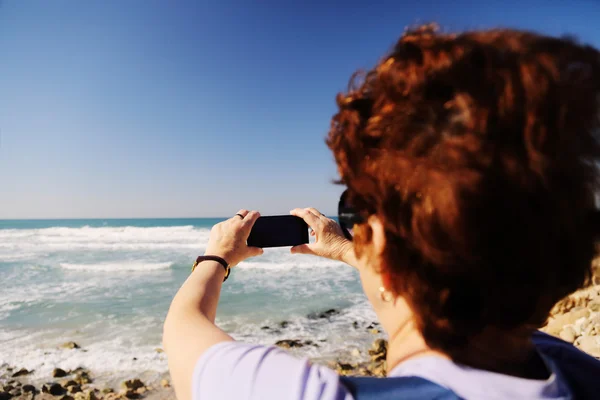 Женщина фотографирует море — стоковое фото
