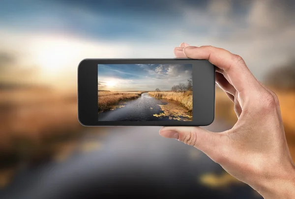 Telefoon in de hand en landschap — Stockfoto