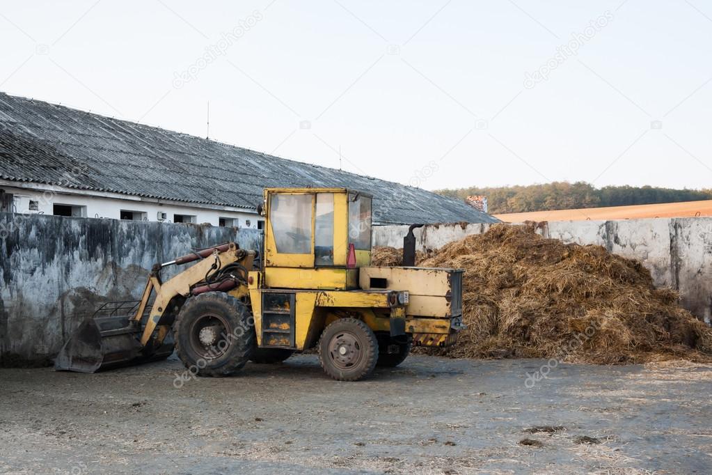 Old bulldozer near heap of manure