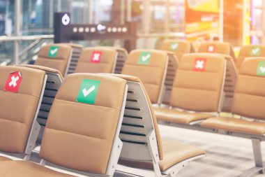 Uluslararası havaalanındaki koltukta sembol çıkartması. Yeni Normal ve Sosyal Mesafe Kavramları, Koronavirüs Hastalığı (Covid-19) enfeksiyonu