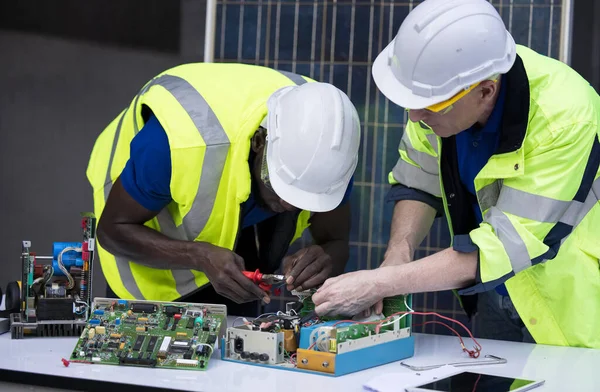 Engineer working repairing electric panel with solar panels background, Concept teamwork or training of renewable.