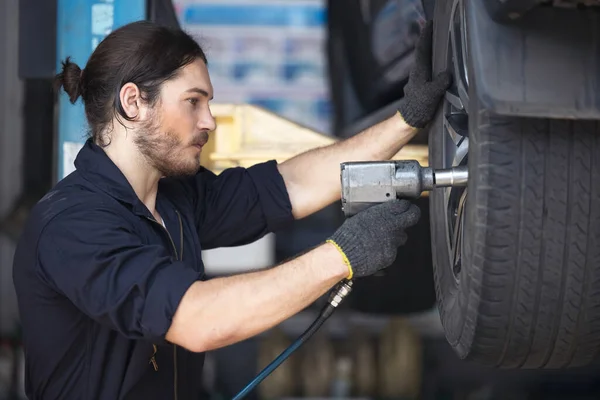 Mechanics Fixing Car Tires At Garage