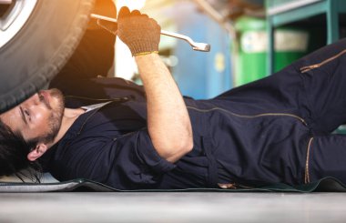 Tamir istasyonunun garajında çarpışma silahıyla tamirci araba lastiği.