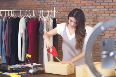 Güzel bir Asyalı kadın birkaç kutunun arasında duruyor ve paketlere bakıyor, ofiste çalışıyor. Ev üssü işletme ve girişim mülkiyeti kavramı