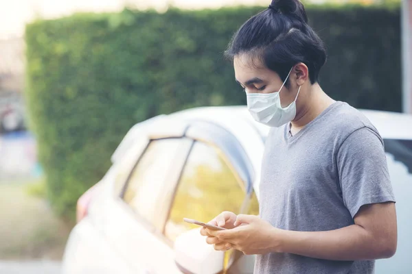 Asia man wearing a medical mask and using a phone outdoors