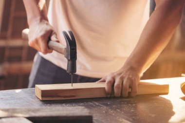 Genel olarak çalışan genç bir marangoz, atölyede, arka planda ahşap bir değirmen makinesi olan ahşap bir bara eşittir.