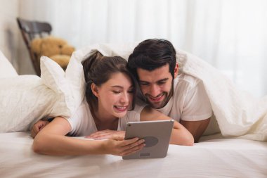 Yataktaki Tatlı Çift 'i kapatın Tablet Gadget' ta bir şey seyredin, yatak odasında dinlenin..