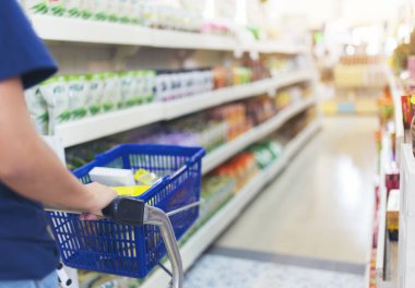 Alışveriş arabalı kadın müşterinin elini kapat, süpermarkette alışveriş arabası. Odaklanmış bokeh ışık geri gruplandırması