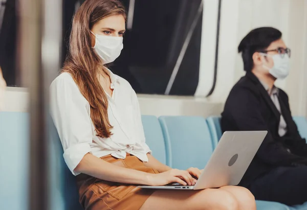 Working woman working with laptop and wearing hygienic mask prevent corona virus at Sky train station