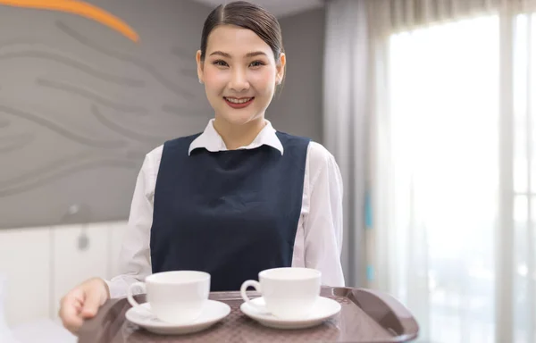 Hotel service concept. Chambermaid holding tray with cup of coffee