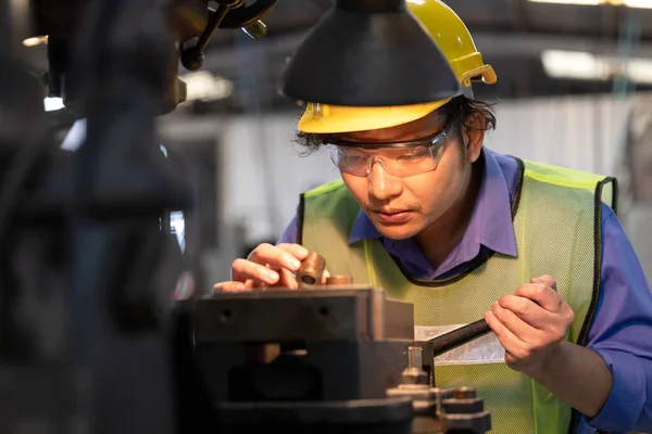 A worker in glasses standing near industrial equipment and verifies production. man operating machine in the factory