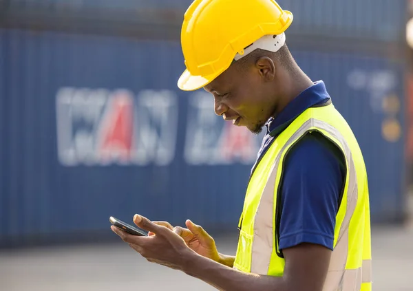 African American black men workers playing, online chatting or browsing on mobile phone while taking a break at construction site