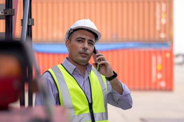 Lojistik kargo konteynırlarının nakliye sahasında çalışan ve konuşan işçi miğferi.