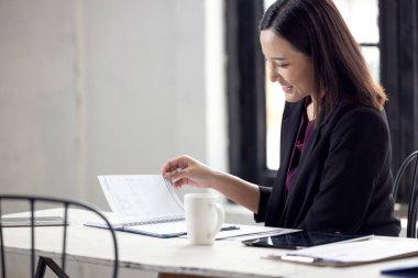 Asyalı işkadını masa evrakları üzerinde çalışıyor.