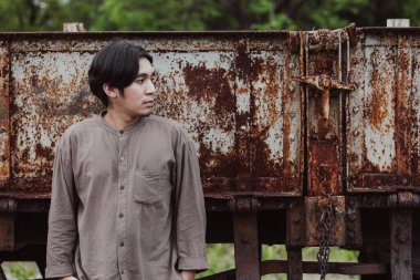 Halka açık tren istasyonunda duran yakışıklı Asyalı adamın portresi. Genç Adam Eski Trende Duruyor