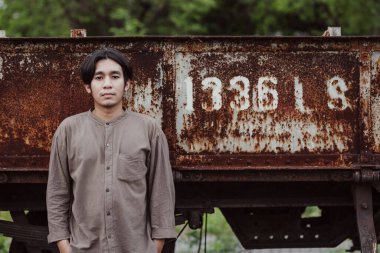 Halka açık tren istasyonunda duran yakışıklı Asyalı adamın portresi. Genç Adam Eski Trende Duruyor