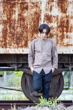 Halka açık tren istasyonunda duran yakışıklı Asyalı adamın portresi. Genç Adam Eski Trende Duruyor