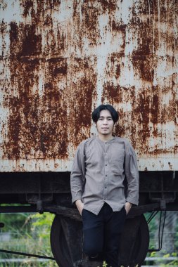 Halka açık tren istasyonunda duran yakışıklı Asyalı adamın portresi. Genç Adam Eski Trende Duruyor