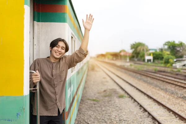 Handsome Young Asian man hand to say hello or goodbye to friend on train, Waving Goodbye