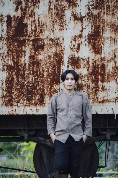 Halka açık tren istasyonunda duran yakışıklı Asyalı adamın portresi. Genç Adam Eski Trende Duruyor