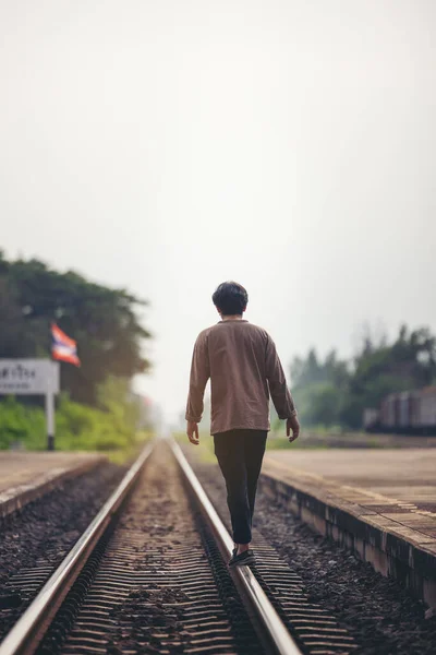 Man walk away on railroad with warm light. Selective focus. Traveler man on railroad.