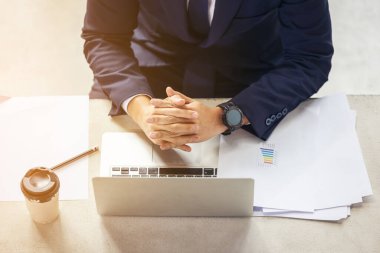 Ofis masasında iş belgeleriyle dizüstü bilgisayarda yazan adamın üst görünümü