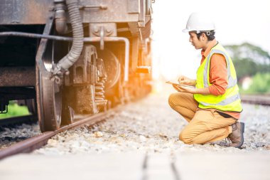 Demiryolu teftişinde oturan mühendis. Demiryollarında inşaat işçisi. Trenin raporlanması için tablet kullanan mühendis çalışması.