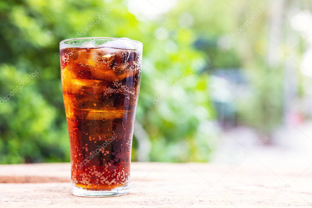 Glass of cola with ice on wood table, soft drink. Copy Space.