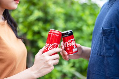 BANGKOK, THAILAND - 15 Mayıs 2021: Tarafsız arkaplanda iki el kırmızı Coca Cola kutularını kaldırır 