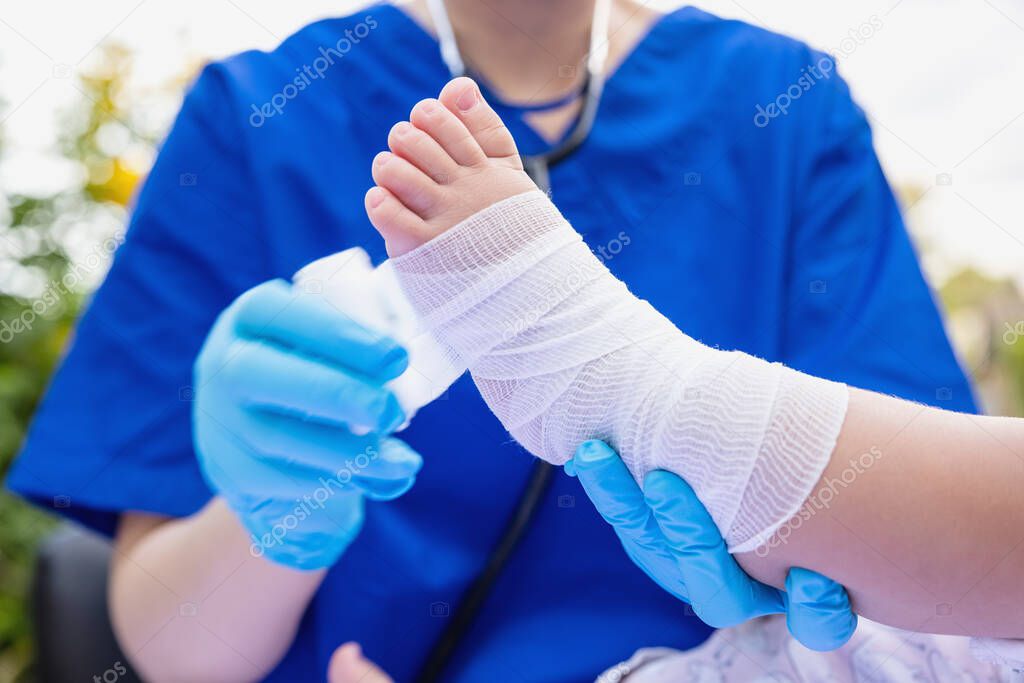 Doctor Rewinds Leg of Small Girl with Bandage. kid's foot was treated bandaging patient`s leg by a doctor.