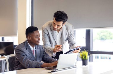 Okulda tablet bilgisayarda çalışan siyahi bir adama yardımcı olan öğretmen