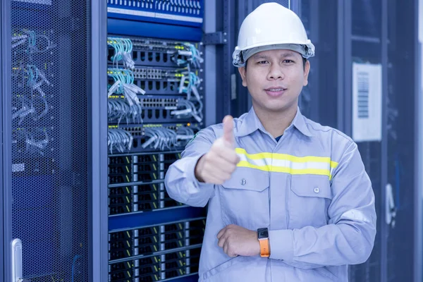 It工程师站在一个有服务器计算机的工作数据中心服务器室内用交叉臂放置在一个Rack上 — 图库照片