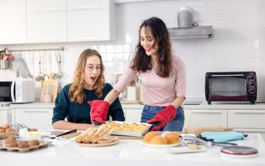 Güzel fırıncı hamur işleri yapıyor, iki güzel mutlu kadın ekmek yaparak eğleniyor ve ellerini hamuru bir araya getirip ev mutfağında kek yapmak için kullanıyor..