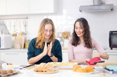 Güzel fırıncı hamur işleri yapıyor, iki güzel mutlu kadın ekmek yaparak eğleniyor ve ellerini hamuru bir araya getirip ev mutfağında kek yapmak için kullanıyor..