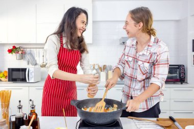 Evde, iki arkadaş mutfakta iyi vakit geçiriyorlar. Rahibeler mutfakta birlikte spagetti hazırlıyorlar. Mutfakta, iki bayan arkadaş.