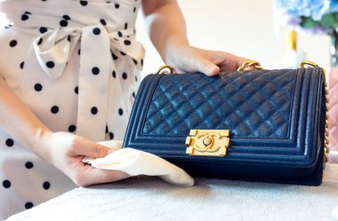 26 Temmuz 2021: Nakhon Prathom, THAILAND, Masada, bir kadın siyah Chanel çanta temizler.