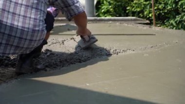 İnşaat işçisinin eldivenli ellerini yakın mesafeden kazımak için mala kullanarak yeni dökülmüş beton bloknotlarla karıştırın.