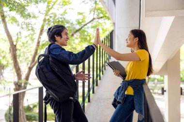 İki Asyalı üniversite öğrencisi muhteşem bir kampüs yolunda sınıfa yürüyüp sohbet ediyorlar..