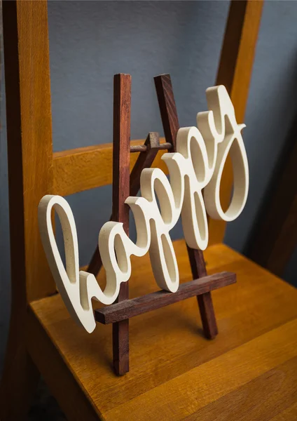 Kalligrafische Inschrift aus Gips "Happy" an der Staffelei — Stockbild Kalligrafische Inschrift aus Gips "glücklich"" — Stockfoto