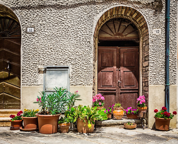 ITALY - JUNE 22, 2014: Windows and doors in an old house decorated with flower pots and flowers