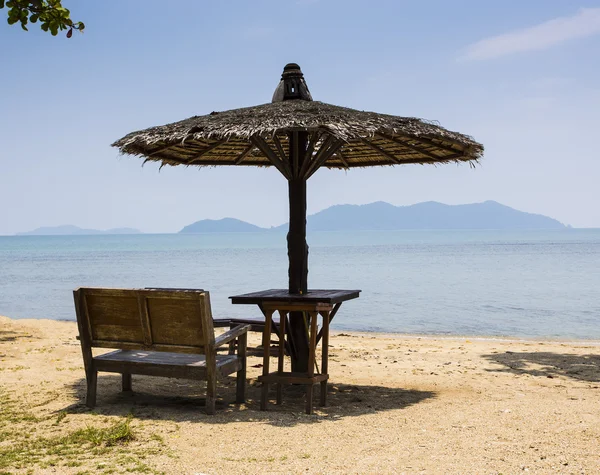 Wooden chairs and umbrella on white beach — Stock Fotó