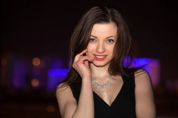 Hermosa joven mujer contra la noche ciudad brillante . — Foto de Stock