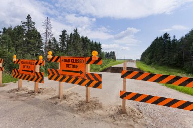 Kapalı yol işaretleri engellenmiş, sel baskınından yıkılmış asfalt hasarlı.