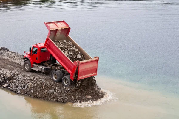 海岸線や港を守る防潮堤の建物に土壌の負荷をダンプ赤いダンプトラック — ストック写真