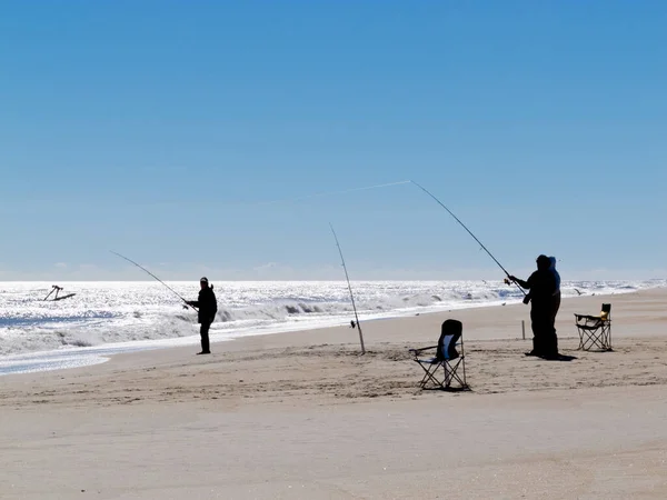 Silhouettes of surf fishing people on sandy beach of Outer Banks, OBX, North Carolina, NC, USA