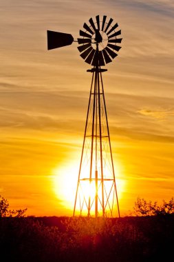 Windpump windmill water pump at sunset in Western Texas, USA clipart