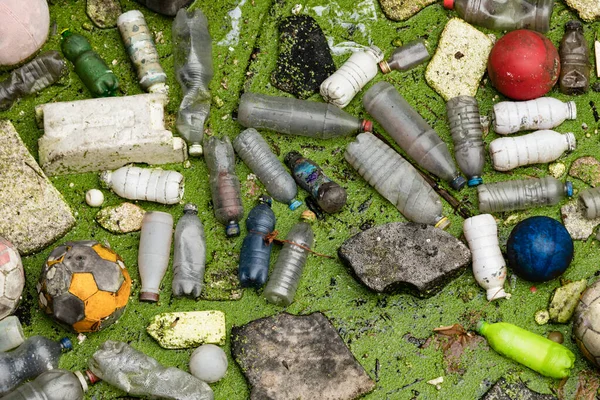 プラスチックごみの汚染の背景 テクスチャパターンプラスチックボトル ゴムボール 発泡スチロールなどの抽象的な概念は 水面に浮かぶ草から緑を拒否します — ストック写真
