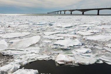 Concrete structure of Confederation Bridge spans frozen Atlantic Ocean between New Brunswick and Prince Edward Island Canada clipart
