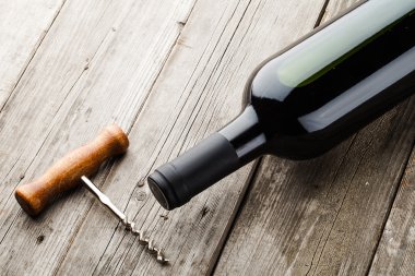 bottle of wine and corkscrew on wooden backgroumd clipart